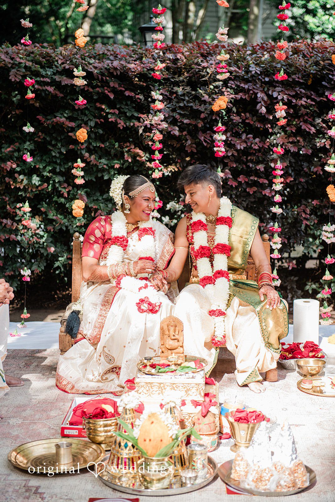 Sonya + Akshaya A bride and groom seated together performing rituals during their wedding ceremony.