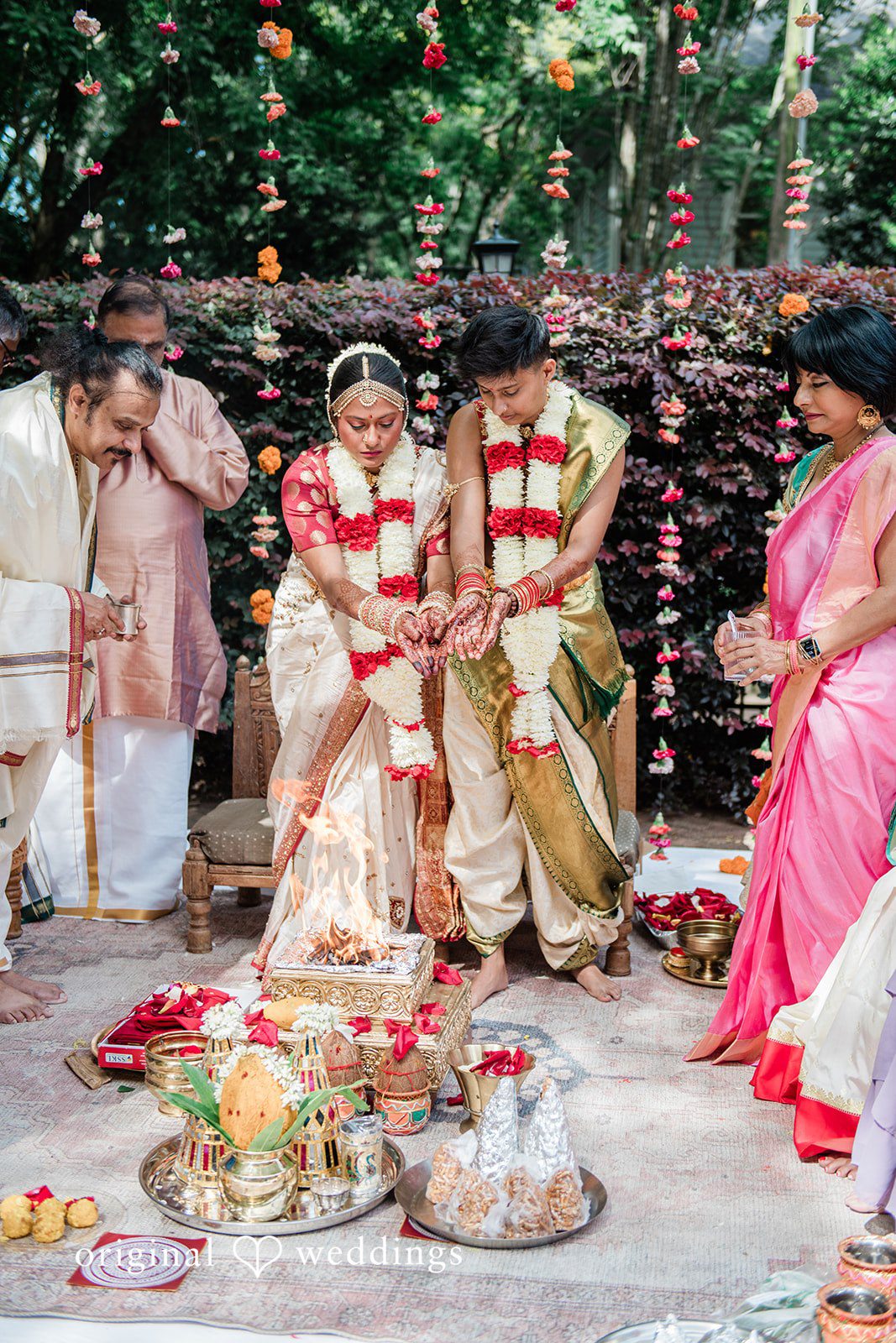 Sonya + Akshaya A bride and groom standing together while wearing traditional flower garlands.