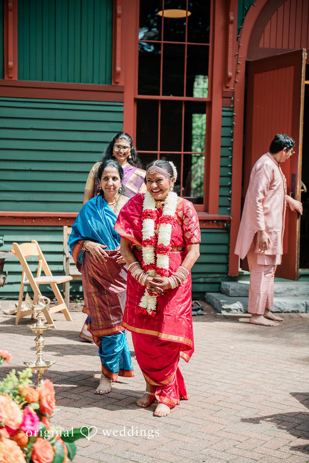 Sonya + Akshaya A bride walking along a pathway near a wooden building.