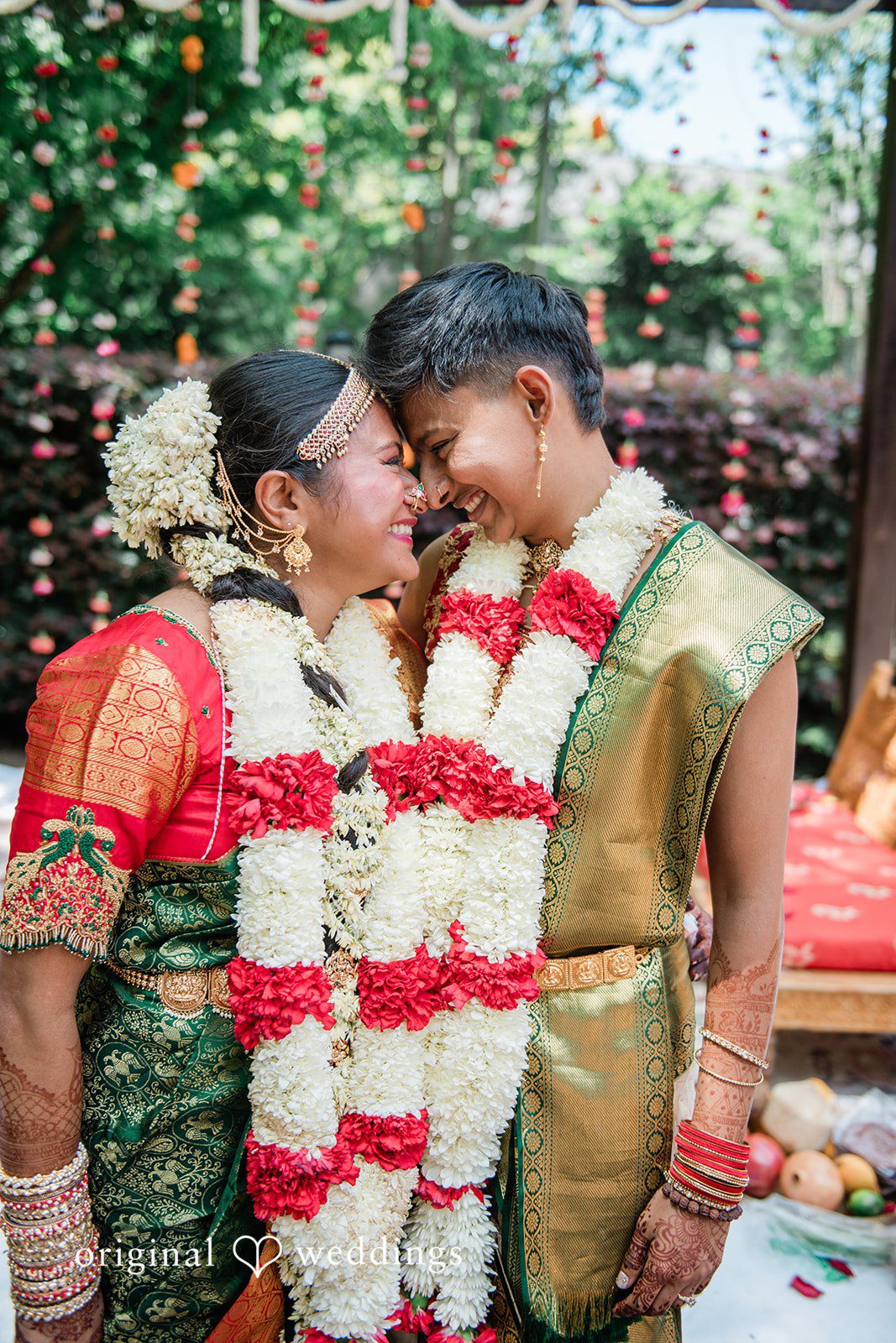 Sonya + Akshaya A bride and groom leaning their heads together while wearing thick flower garlands.