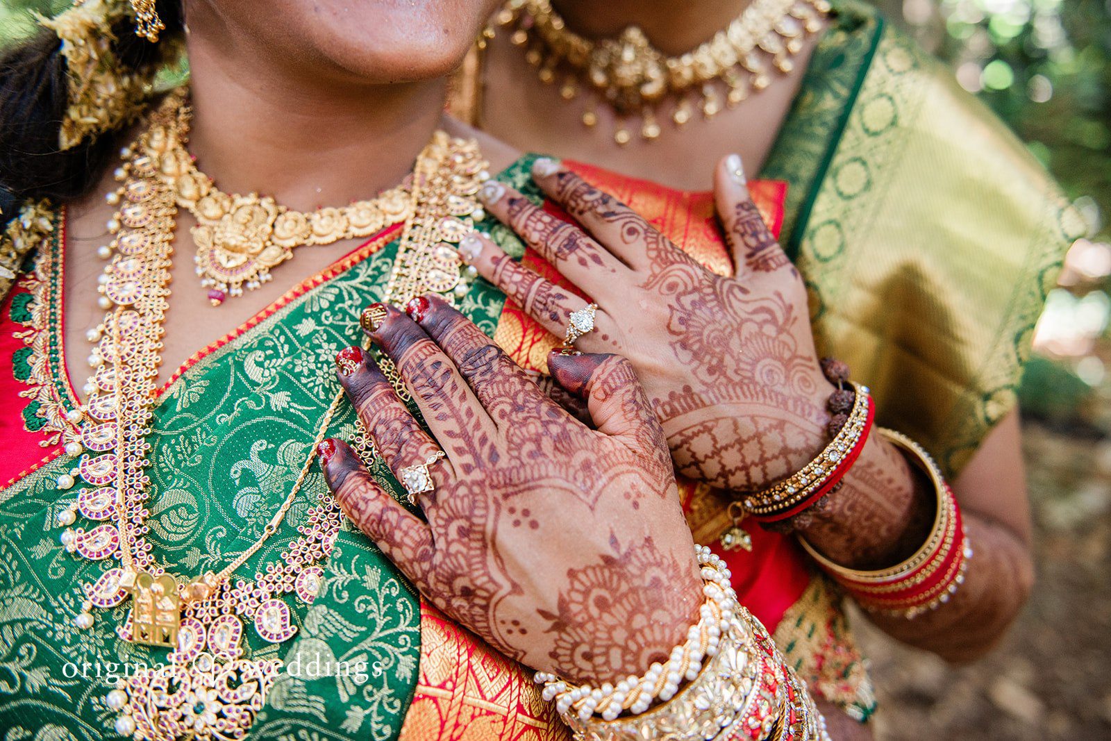 Sonya + Akshaya Close-up of a bride wearing traditional gold jewelry and a green saree.