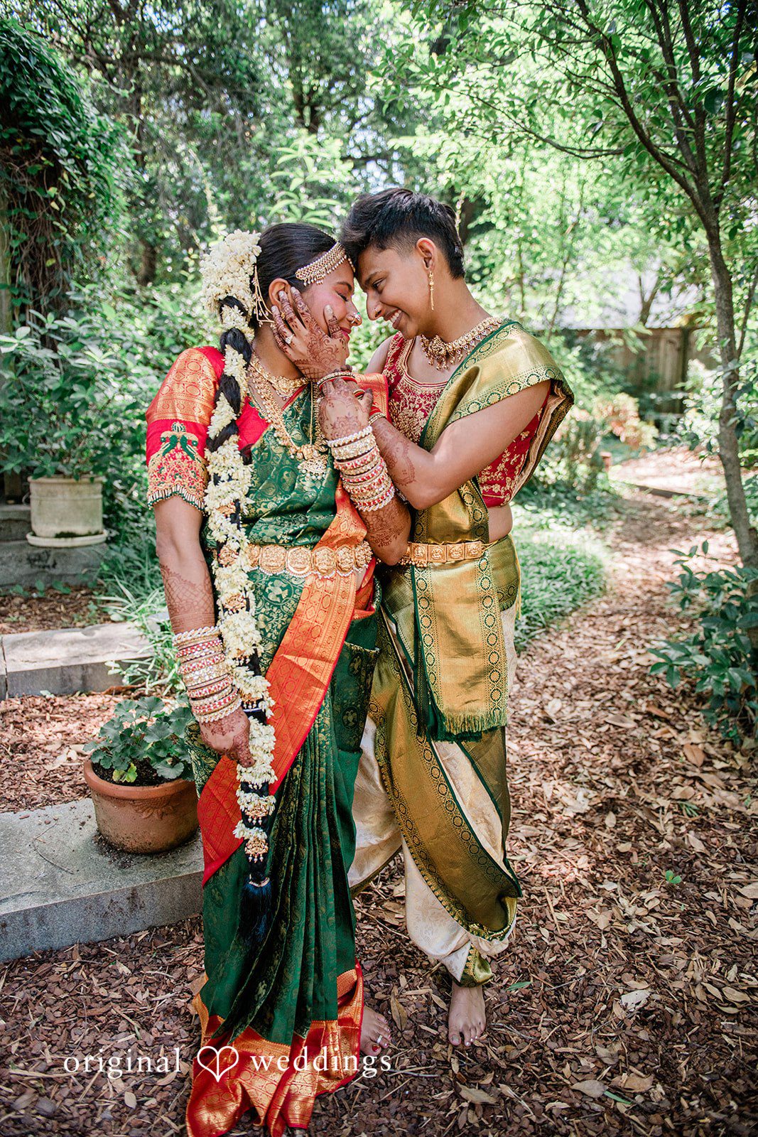 Sonya + Akshaya A couple standing closely together in a lush garden setting.
