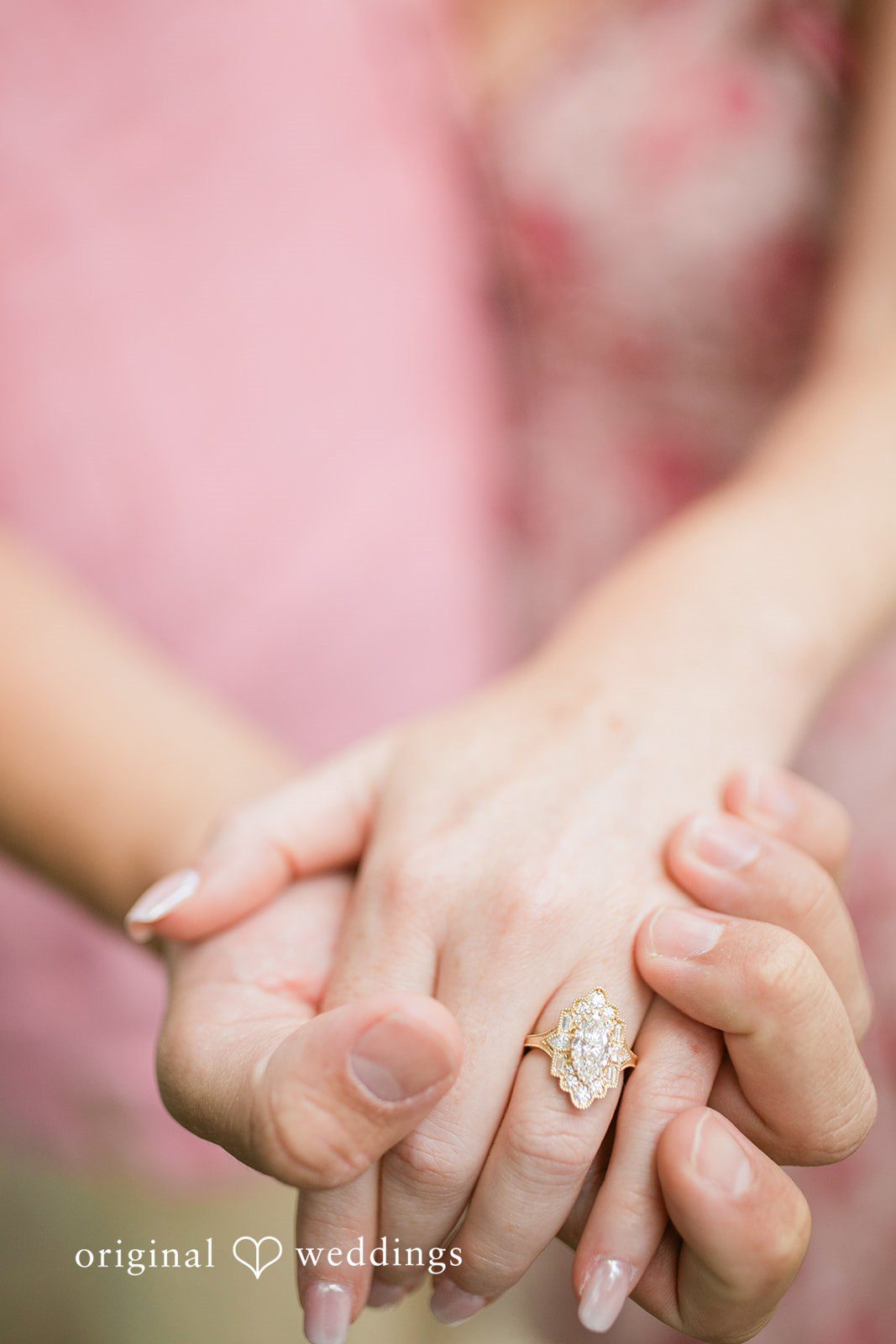 Taylor + Jack Close-up shot of a couple holding hands, highlighting a diamond engagement ring on the woman's finger.