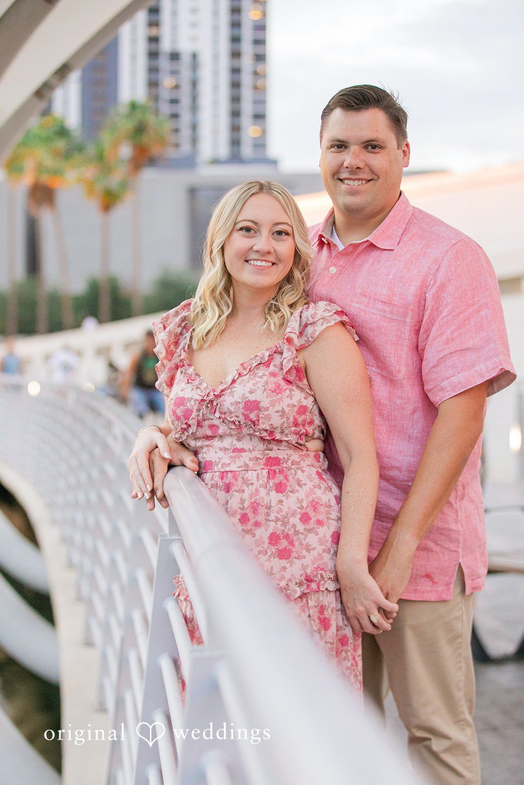 Taylor + Jack Smiling couple posing next to a white bridge structure.