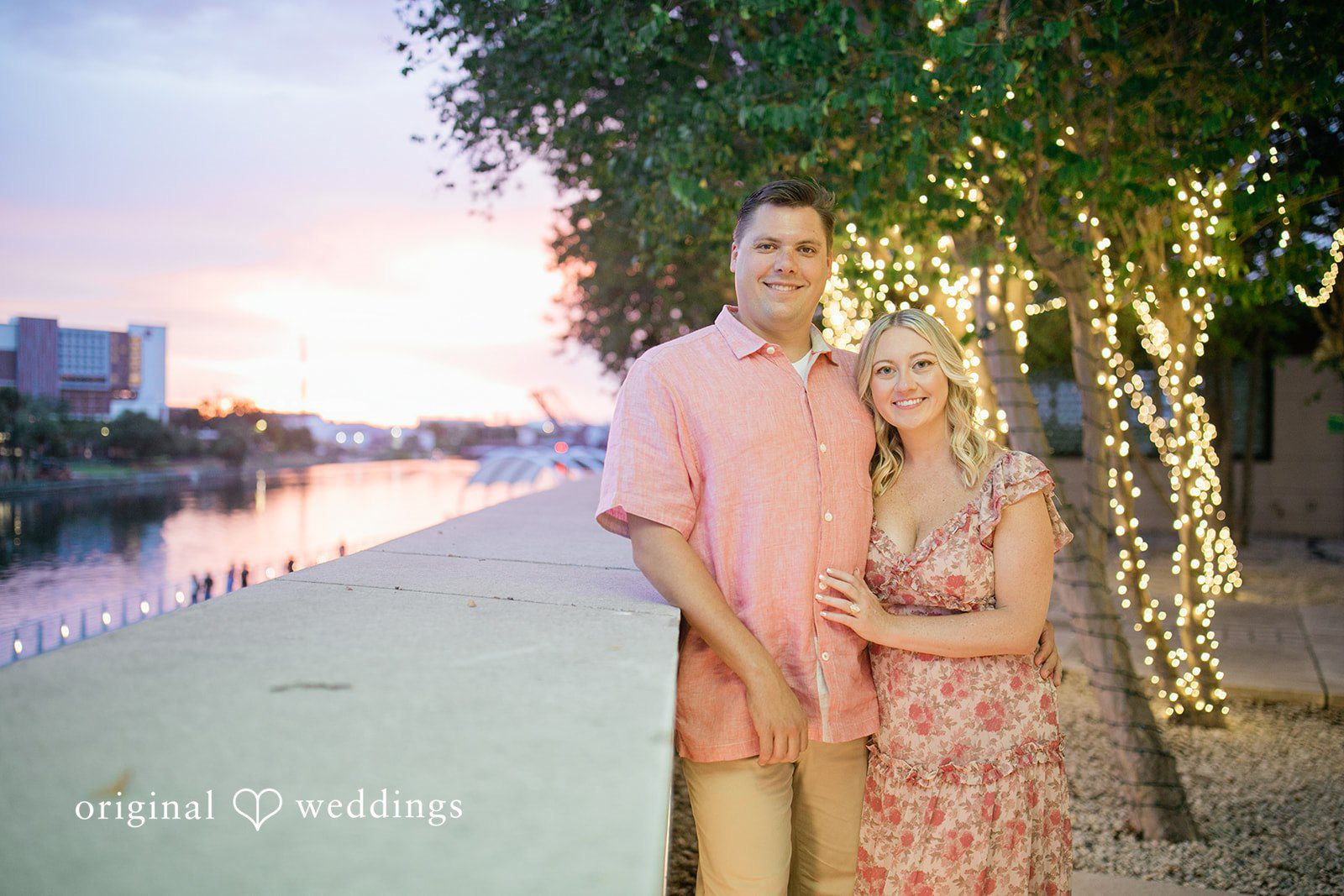 Taylor + Jack Couple standing next to a city waterfront walkway at dusk.