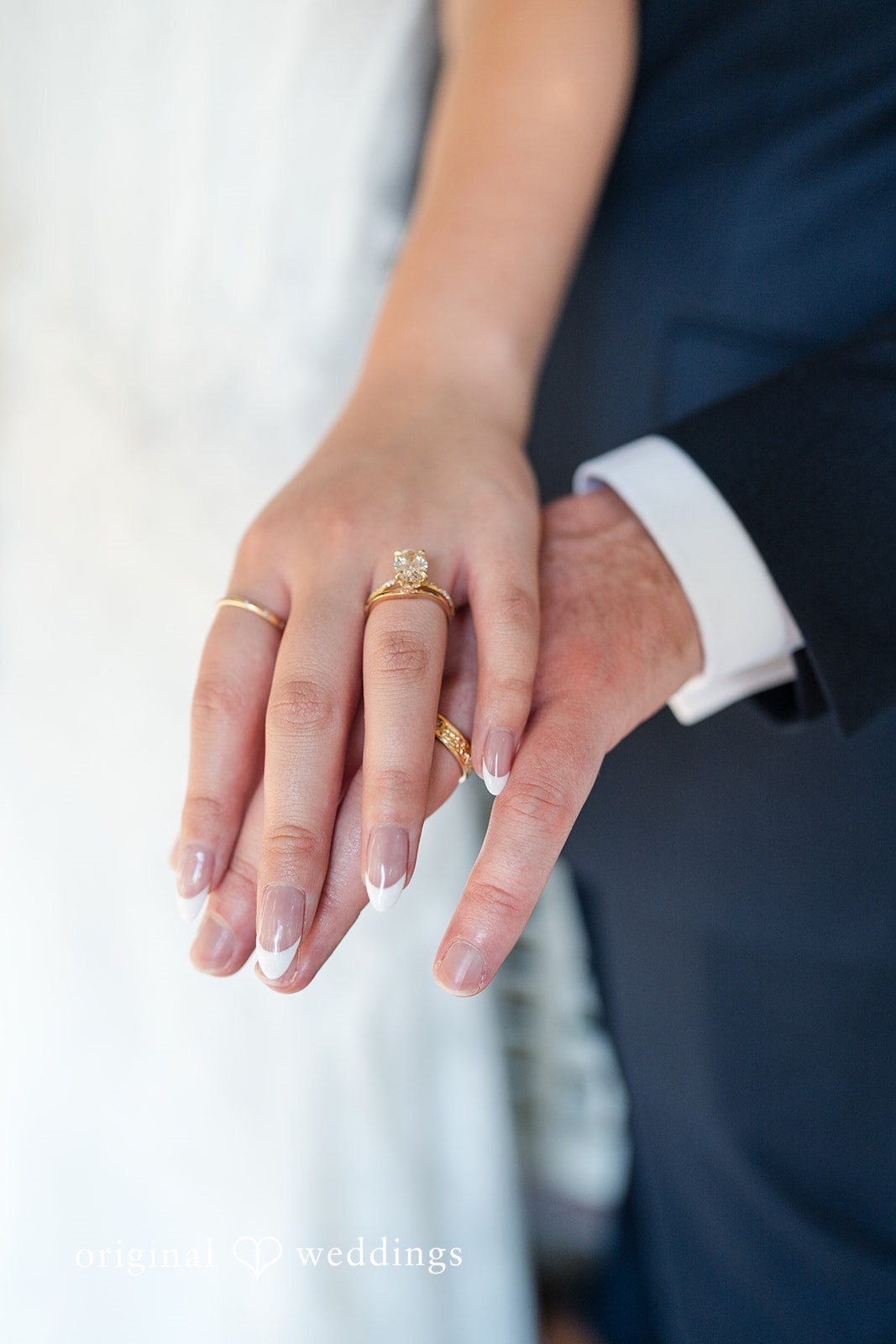 Maya + Max A close-up of a bride and groom's hands showing off their new gold wedding bands.