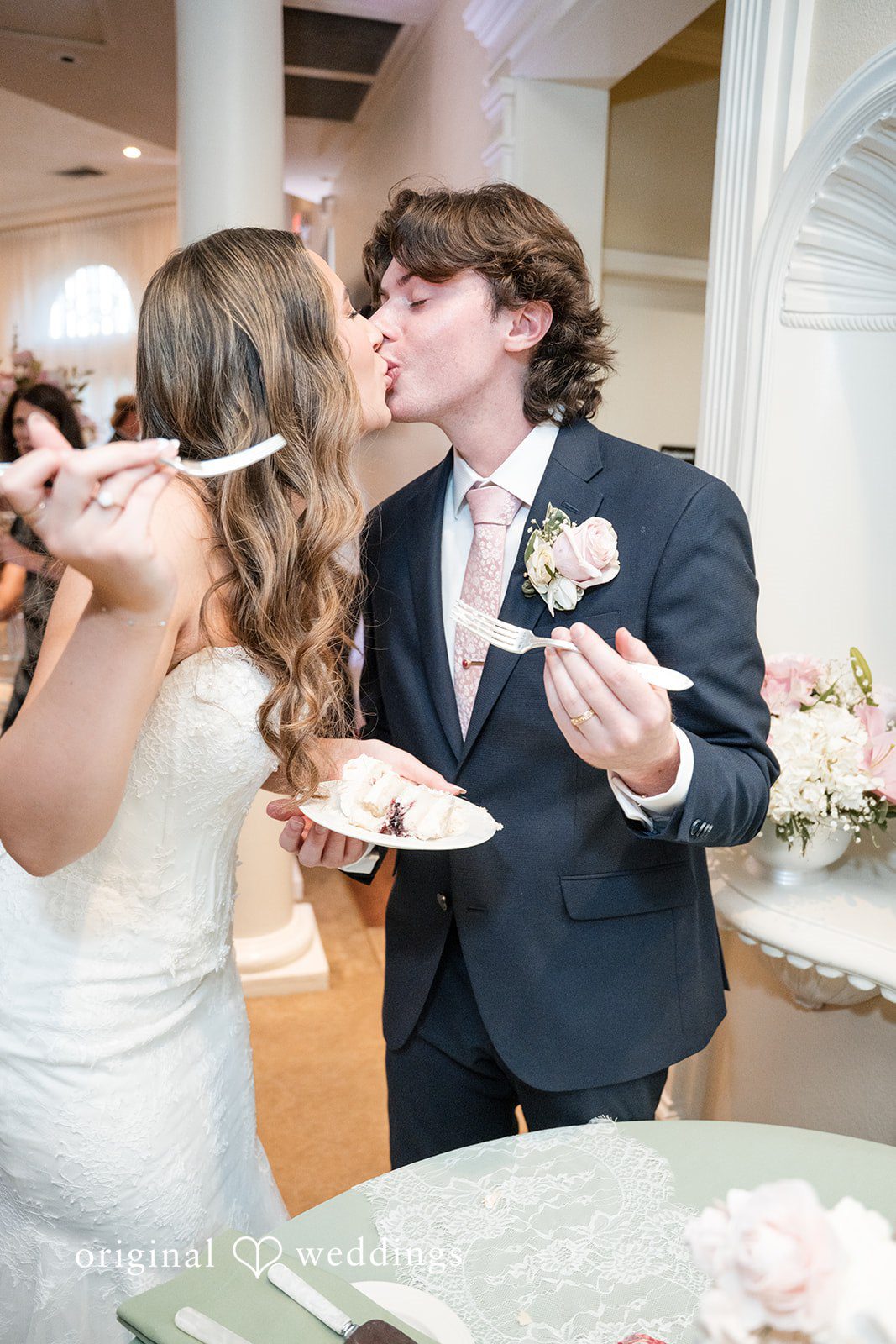 Maya + Max A bride and groom feeding each other slices of wedding cake on forks.