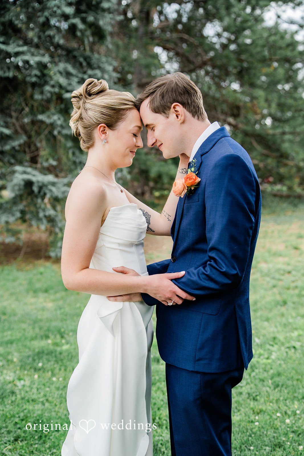 Sophia + Miles A groom embracing the bride from behind while standing on a grassy lawn.