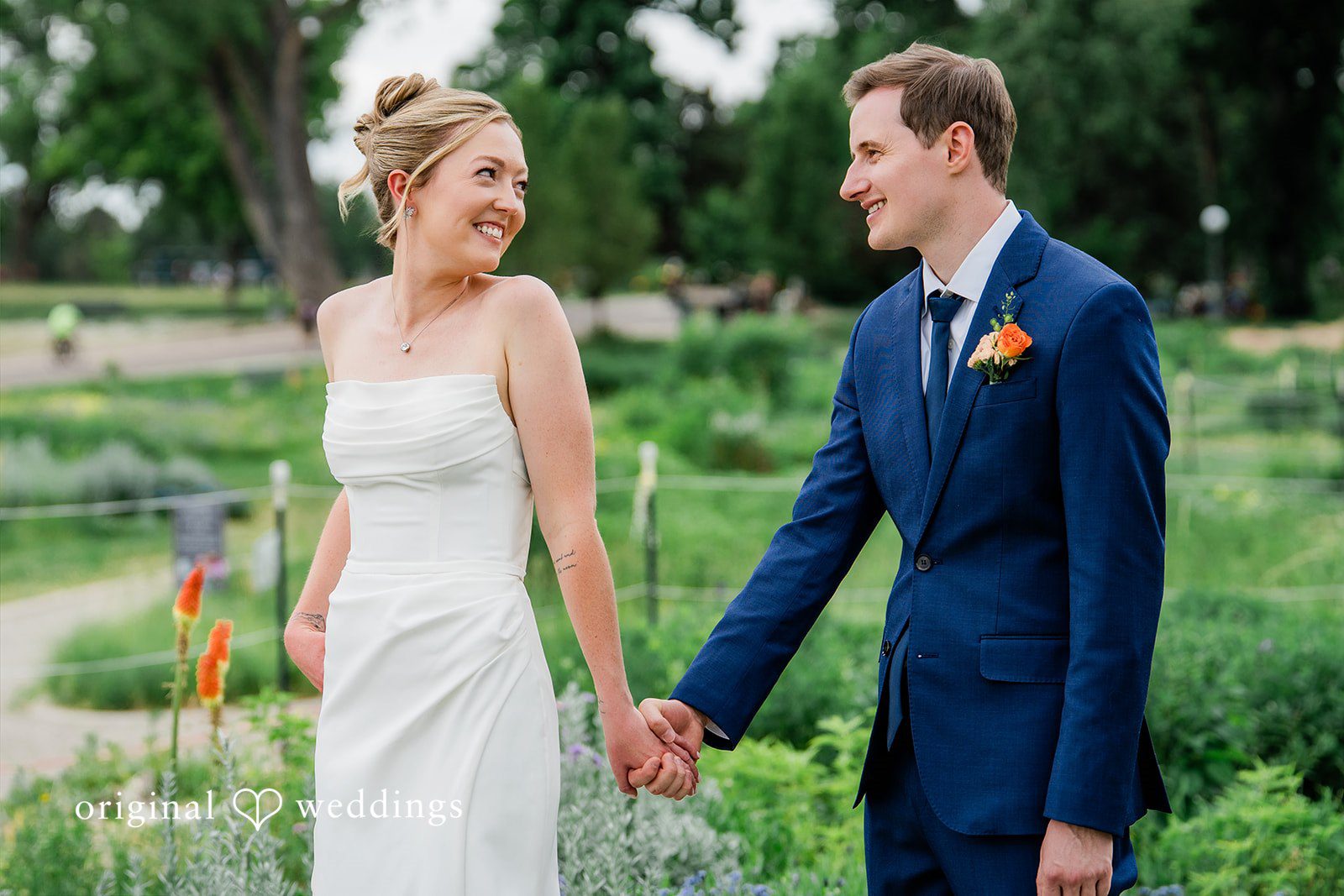 Sophia + Miles A bride and groom holding hands and walking together through a garden.