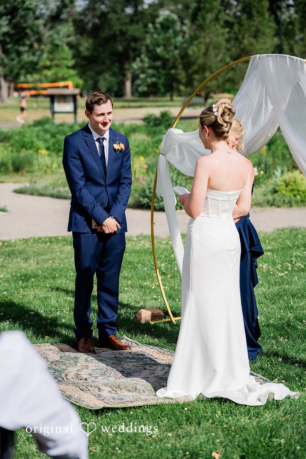 Sophia + Miles A wedding couple exchanging vows at the altar in front of a line of trees.