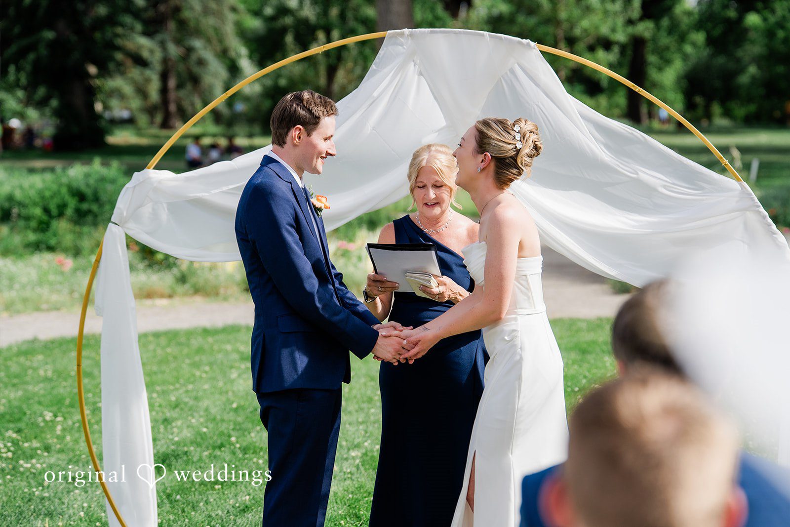 Sophia + Miles Close-up of a bride and groom during their ceremony standing beneath a fabric-draped arch.