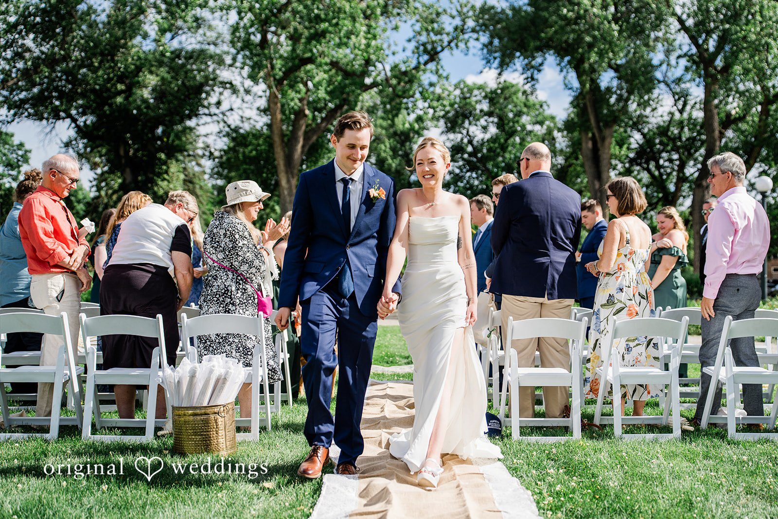 Sophia + Miles A newlywed couple walking back down the aisle together as guests look on.