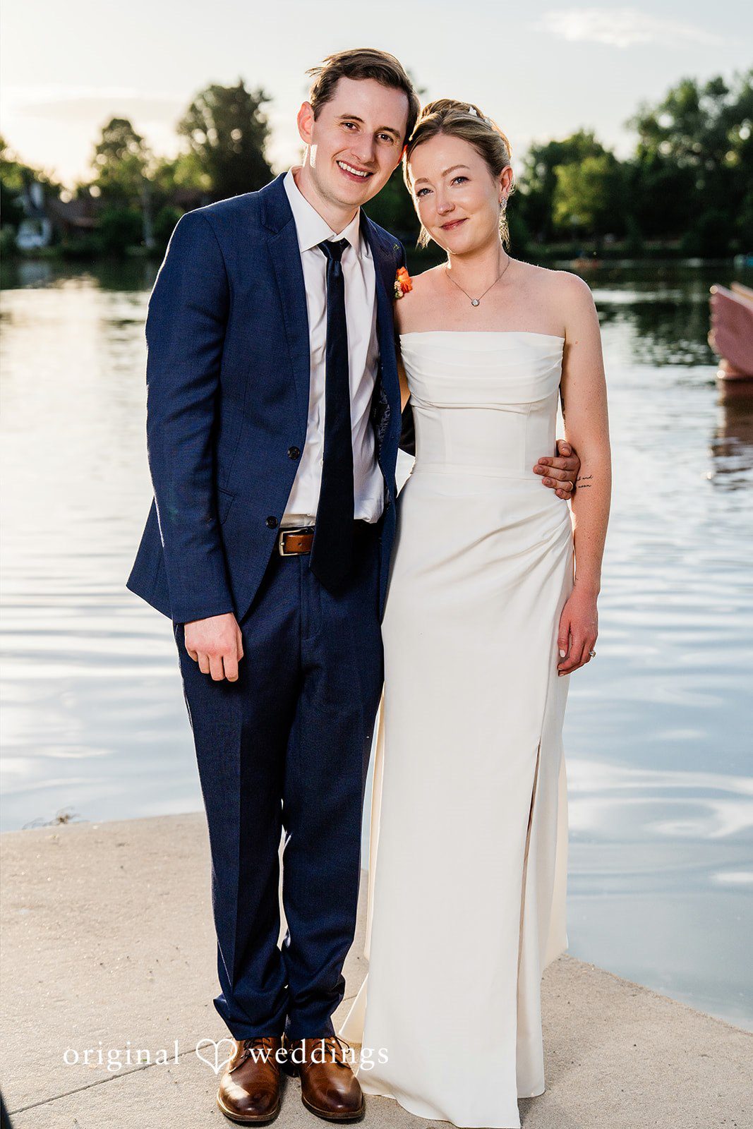 Sophia + Miles A bride and groom posing closely together with a scenic lake behind them.