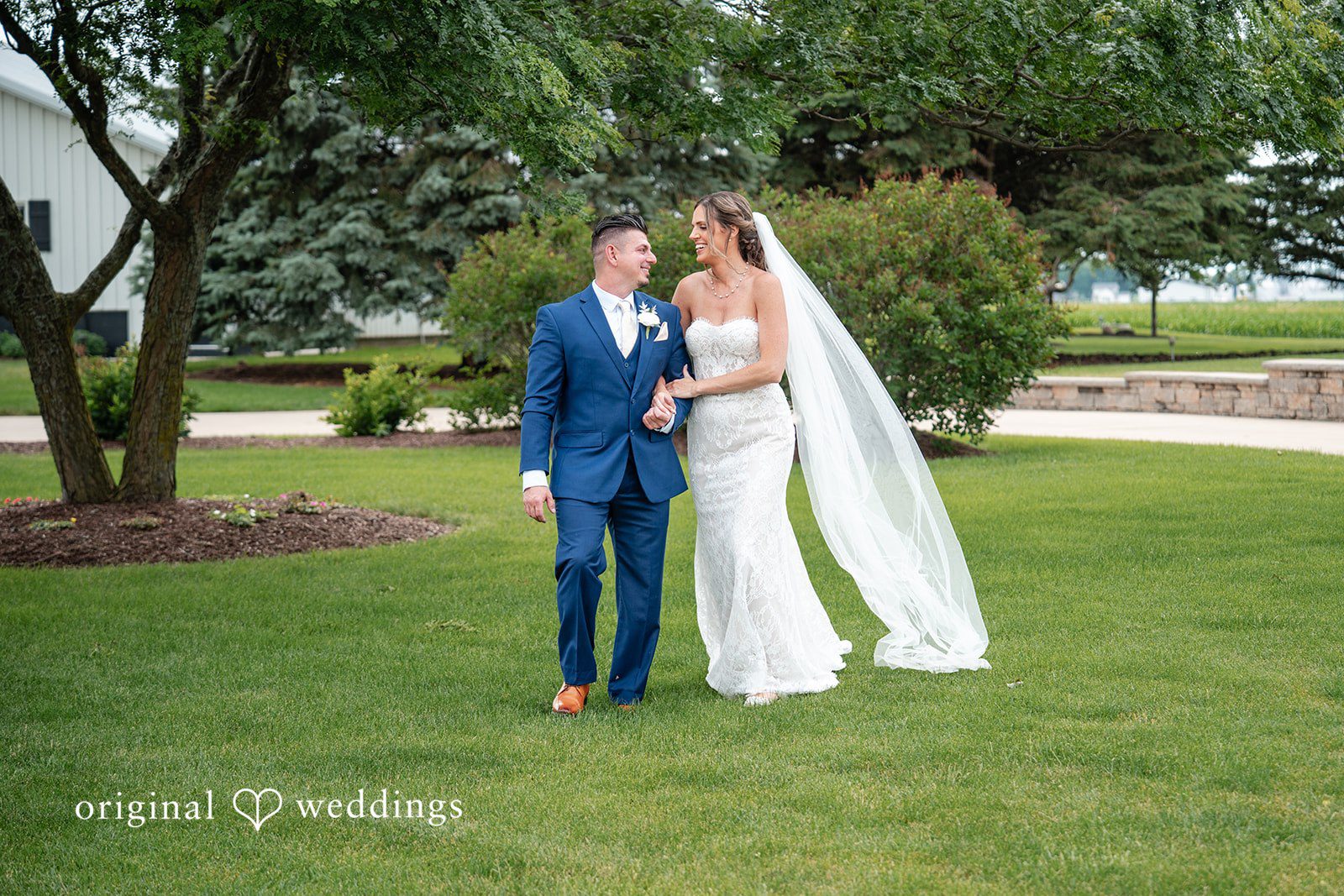 Newlyweds enjoying a relaxed walk across beautifully landscaped wedding grounds