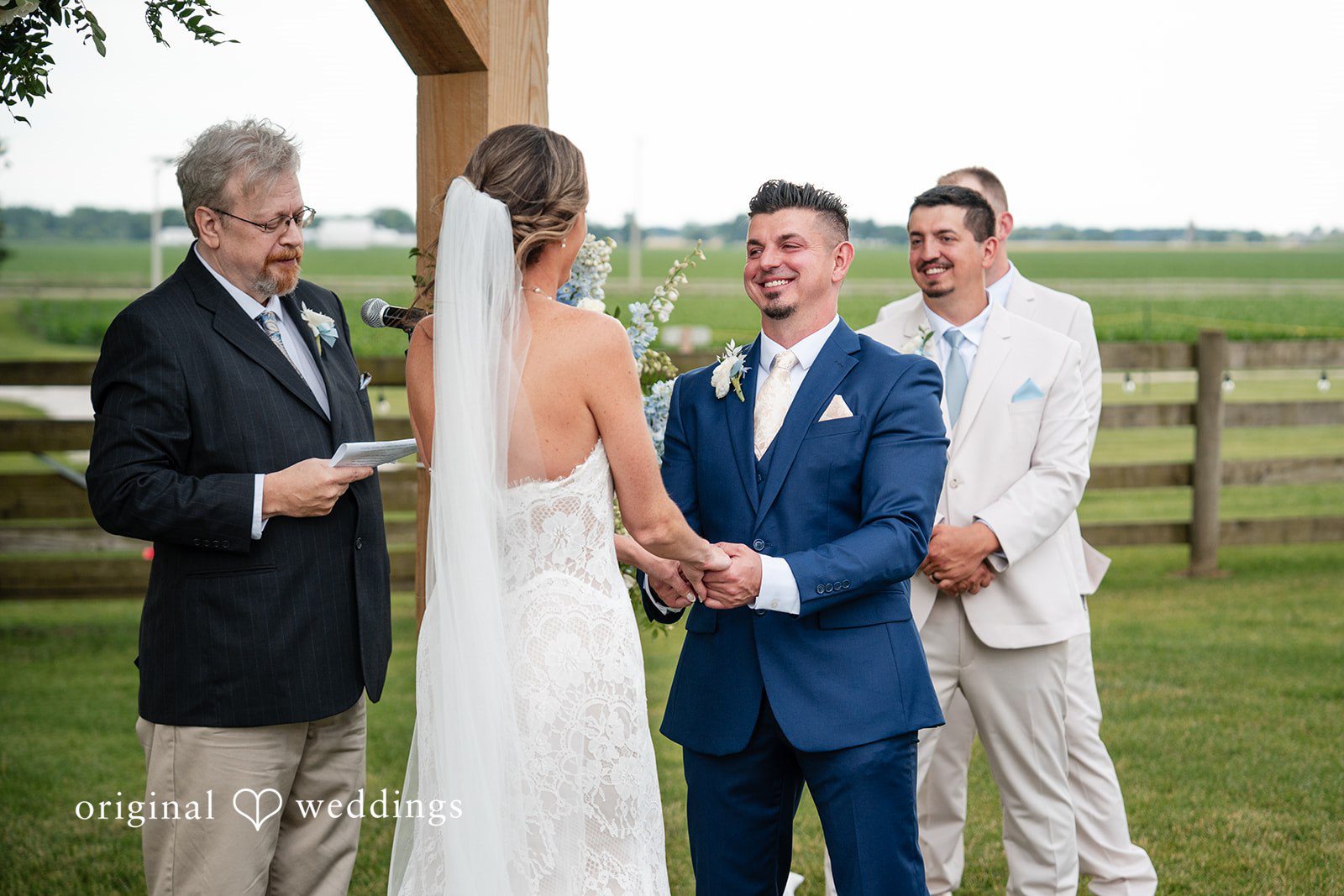 Couple holding hands while exchanging vows surrounded by family and friends