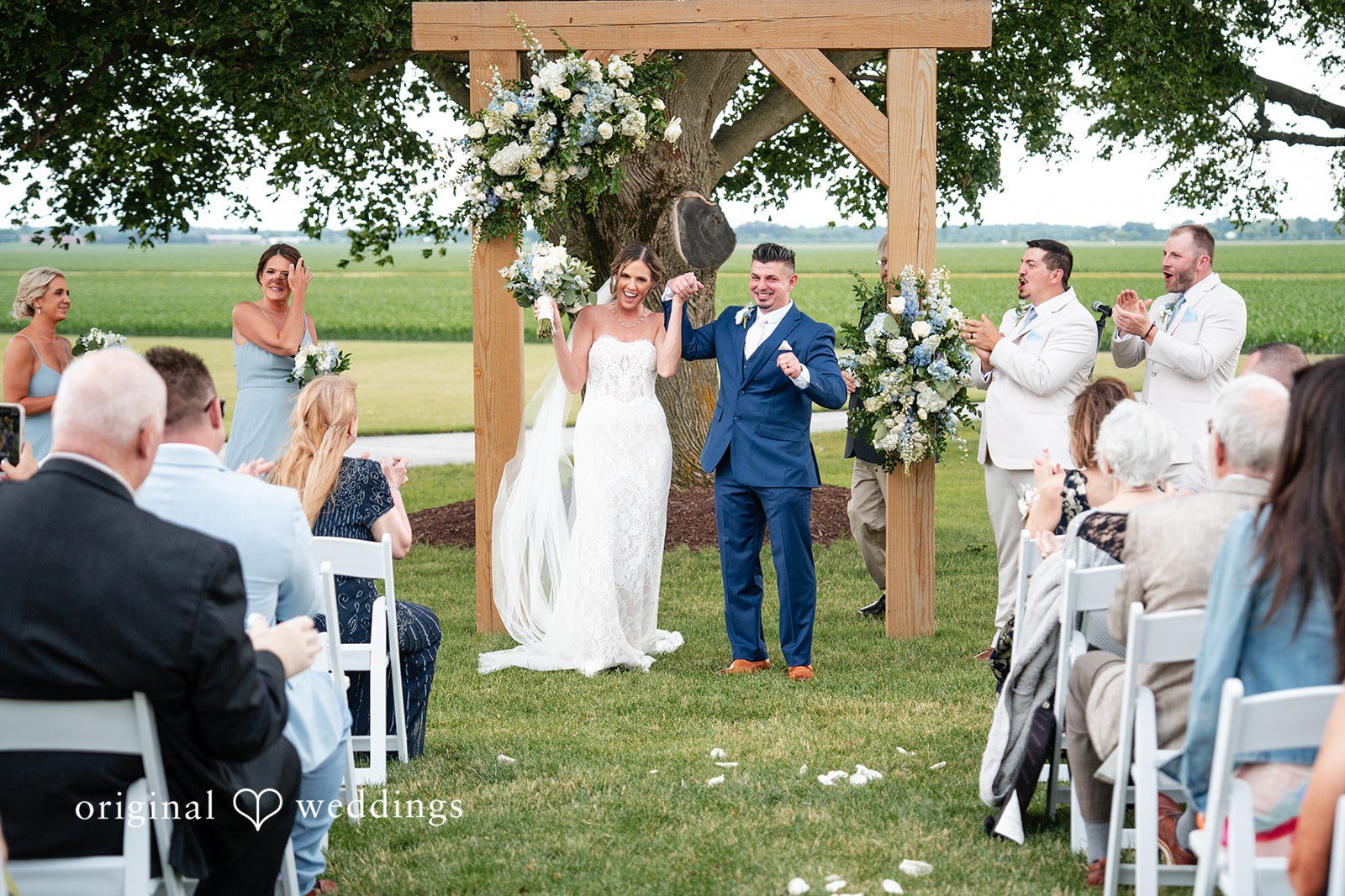 Newlyweds celebrating after their wedding ceremony with cheering guests at White Stone Events captured by Chicago Wedding Photographers from Original Weddings
