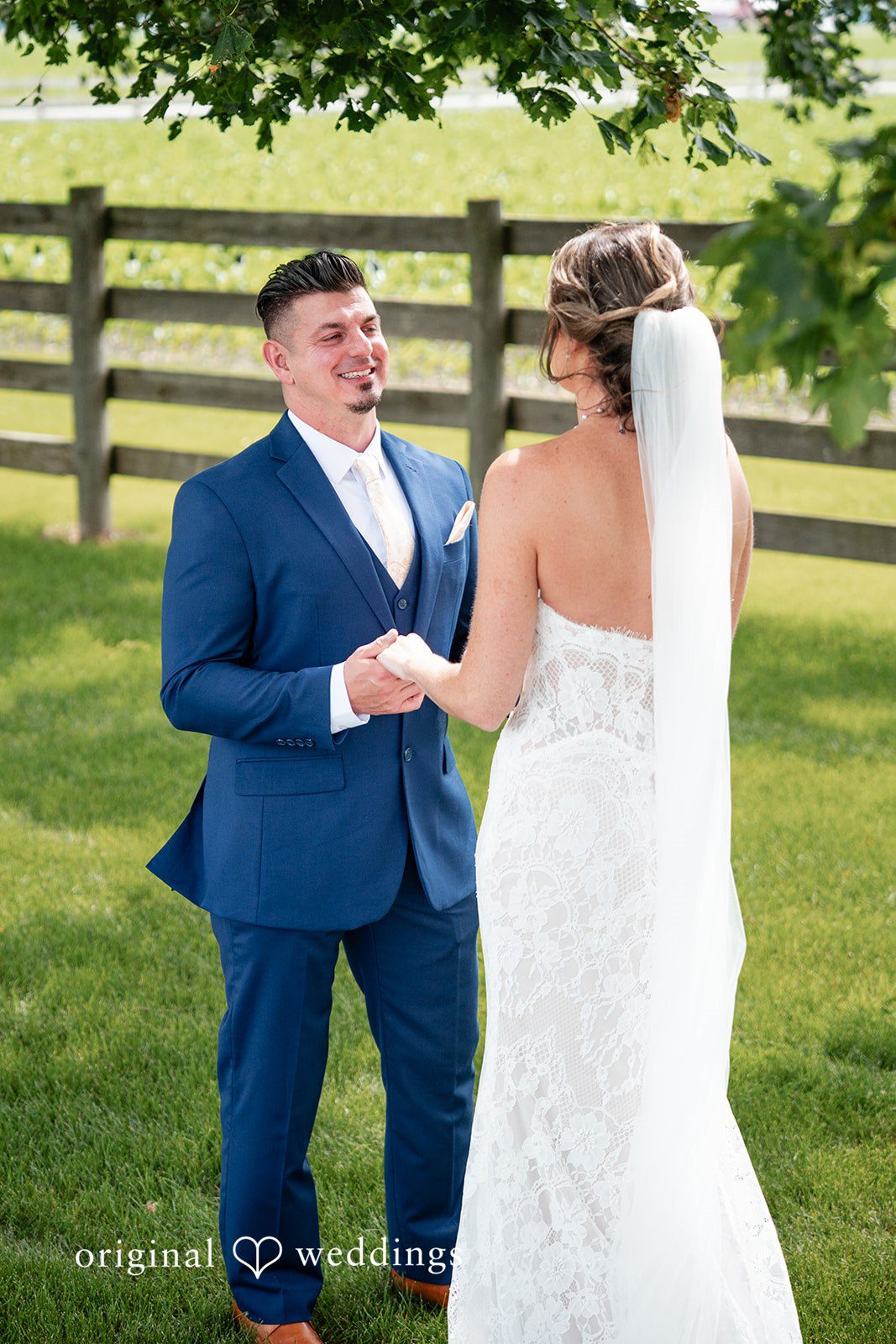 Groom smiling during an emotional first look with his bride outdoors.