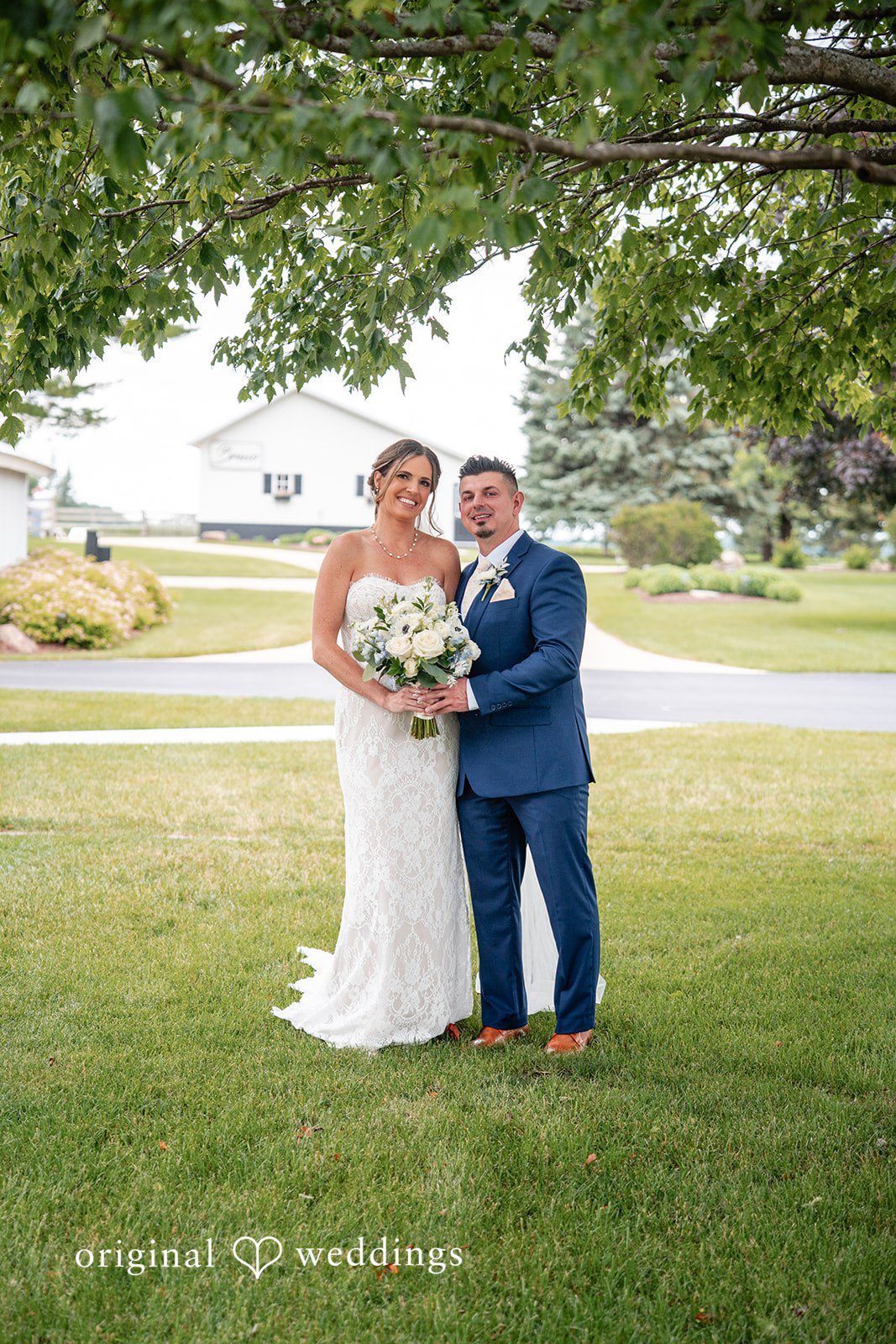 Romantic portrait beneath leafy trees with the bride holding her bouquet.
