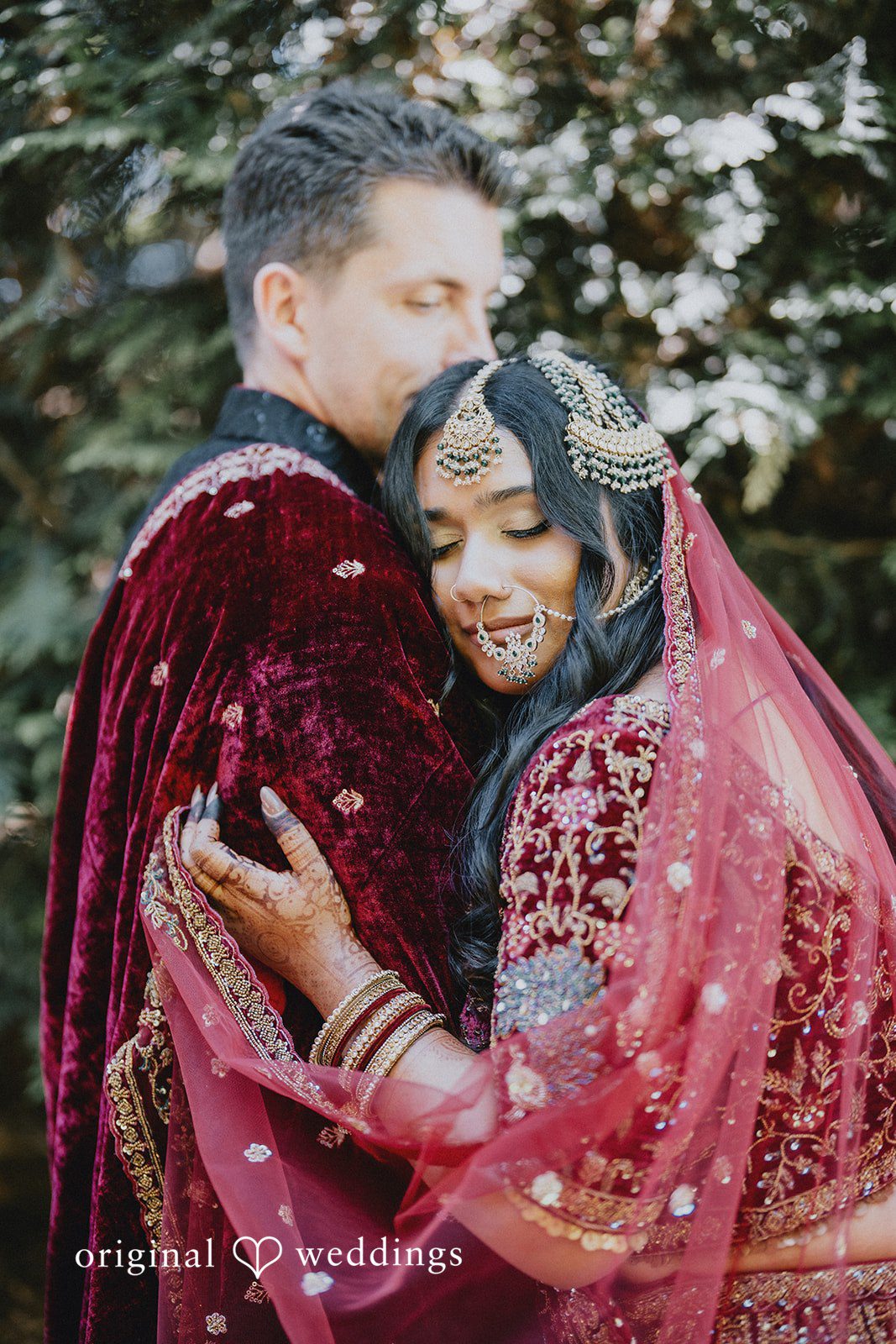 Groom hugging the bride and kissing her forehead with love.