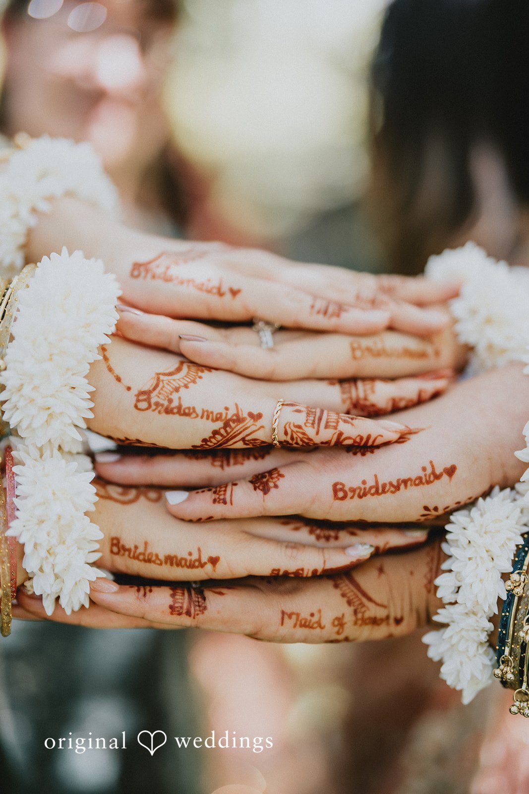 Close-up of bridesmaids' hands stacked together with elegant mehndi artwork at Willows Lodge