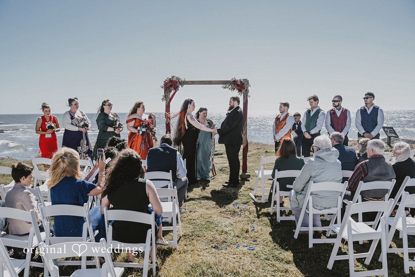 Wedding ceremony setup with guests seated in white chairs facing an altar.