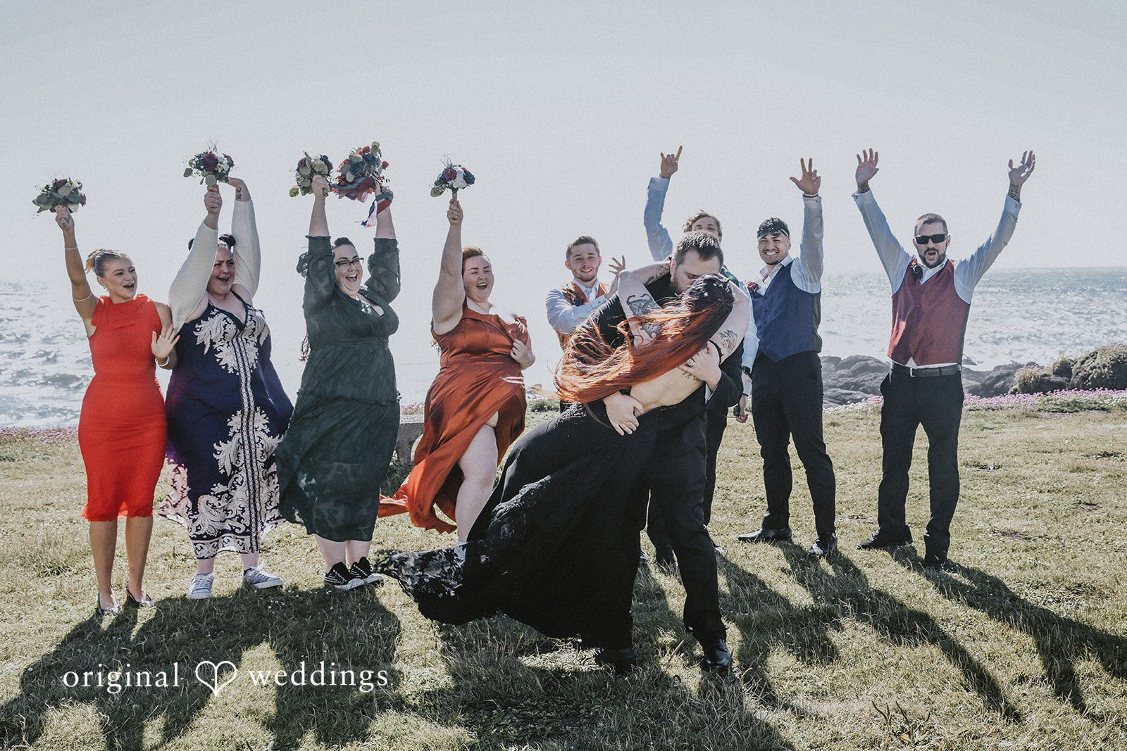 Wedding party cheering with raised arms next to the newlyweds.