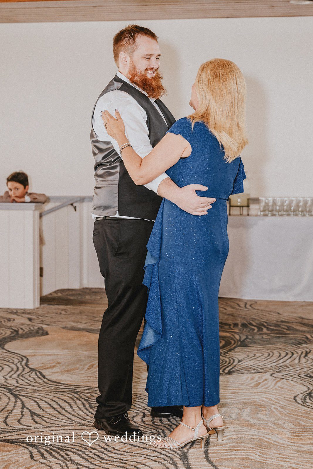 Groom dancing with a woman wearing a blue dress.