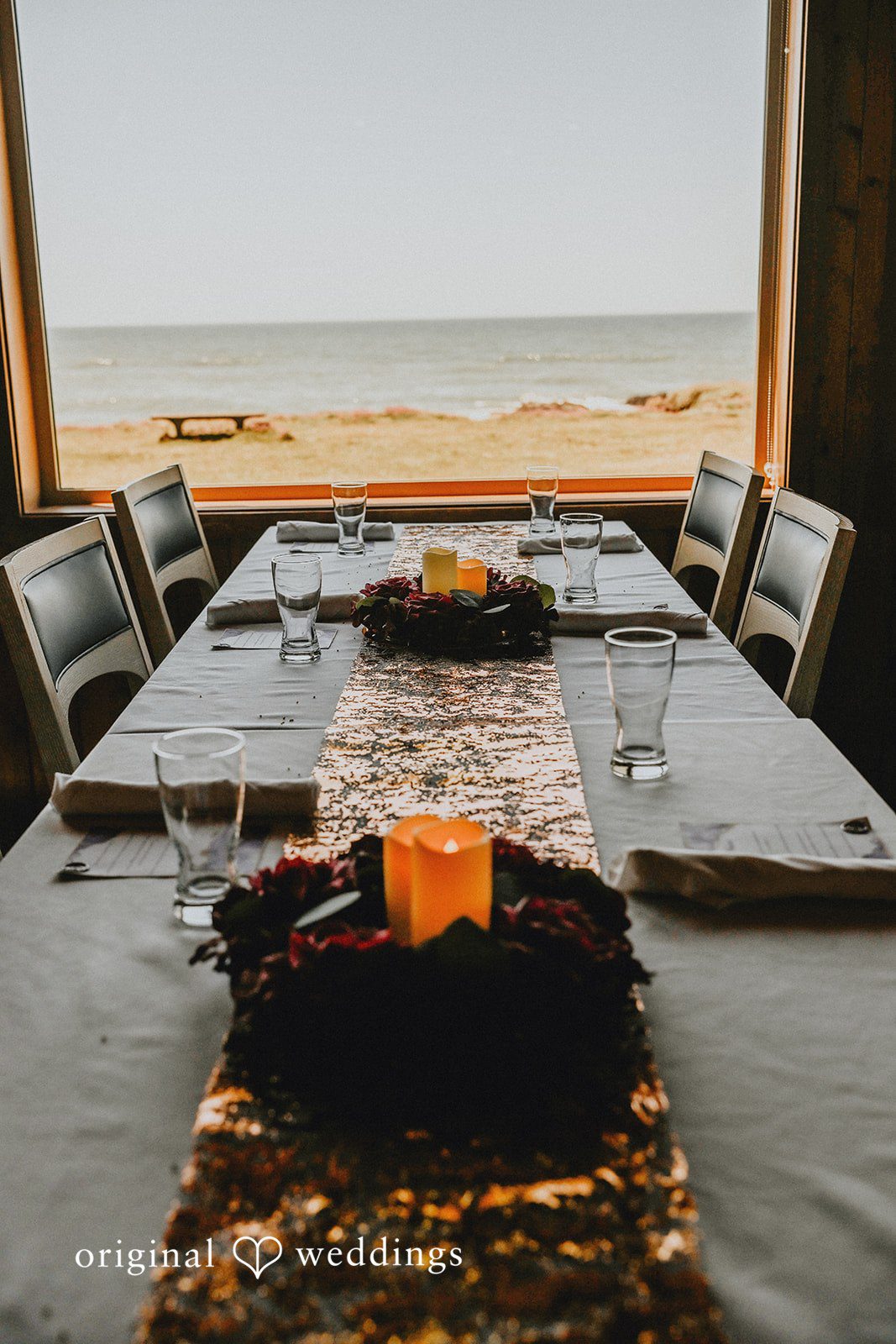 Long wooden dining table set with a dark runner and centerpieces.