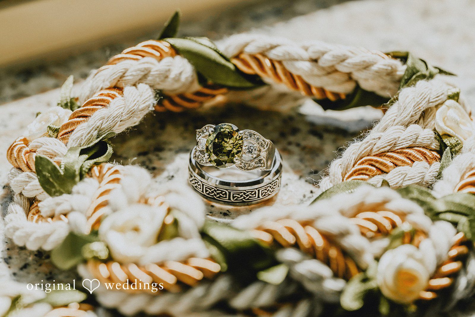 Wedding rings nested inside a woven rope and floral arrangement.