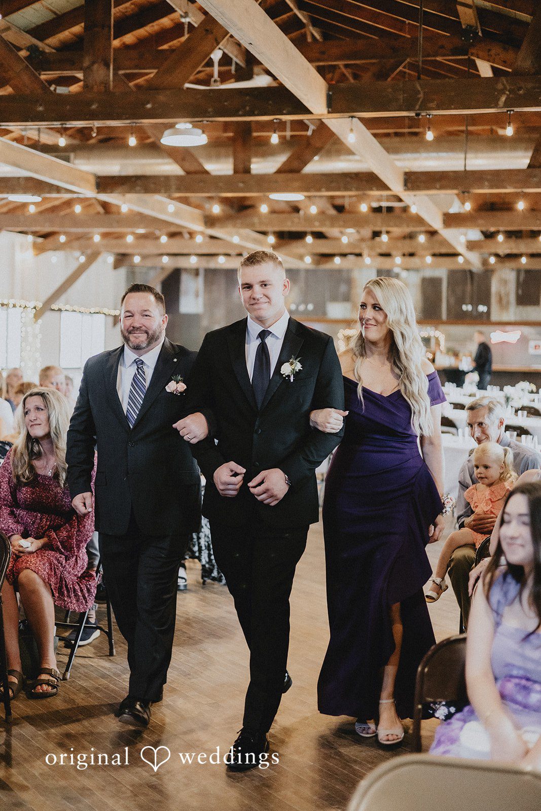 Emily + Ethan Groom walking down an aisle with man and women in a wedding procession.