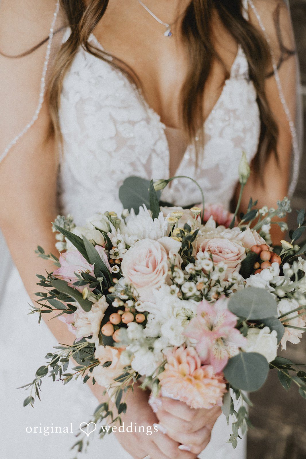 Emily + Ethan Detailed view of a bride holding a large pastel bouquet.