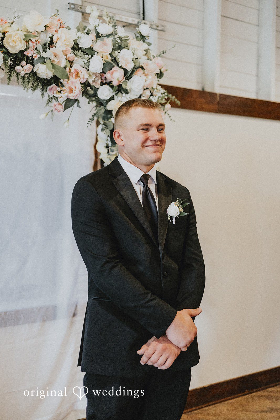 Emily + Ethan Groom waiting at the altar with a happy expression.