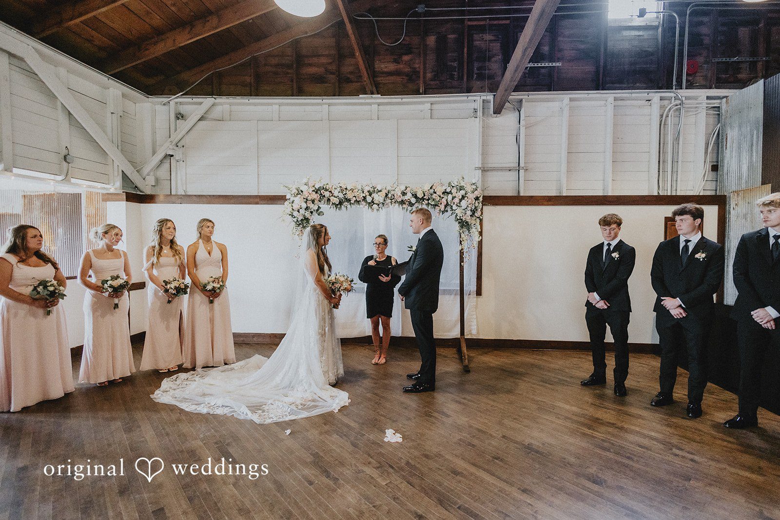 Emily + Ethan Full view of the wedding ceremony taking place in a barn.