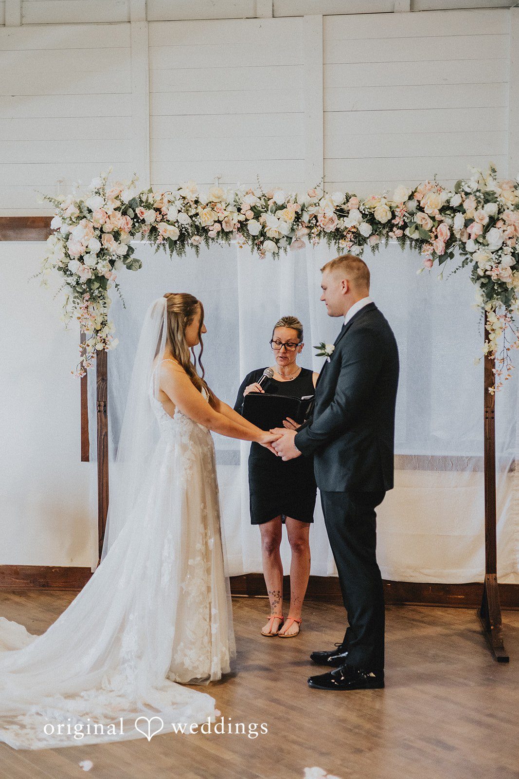 Emily + Ethan Bride and groom holding hands at the floral altar.