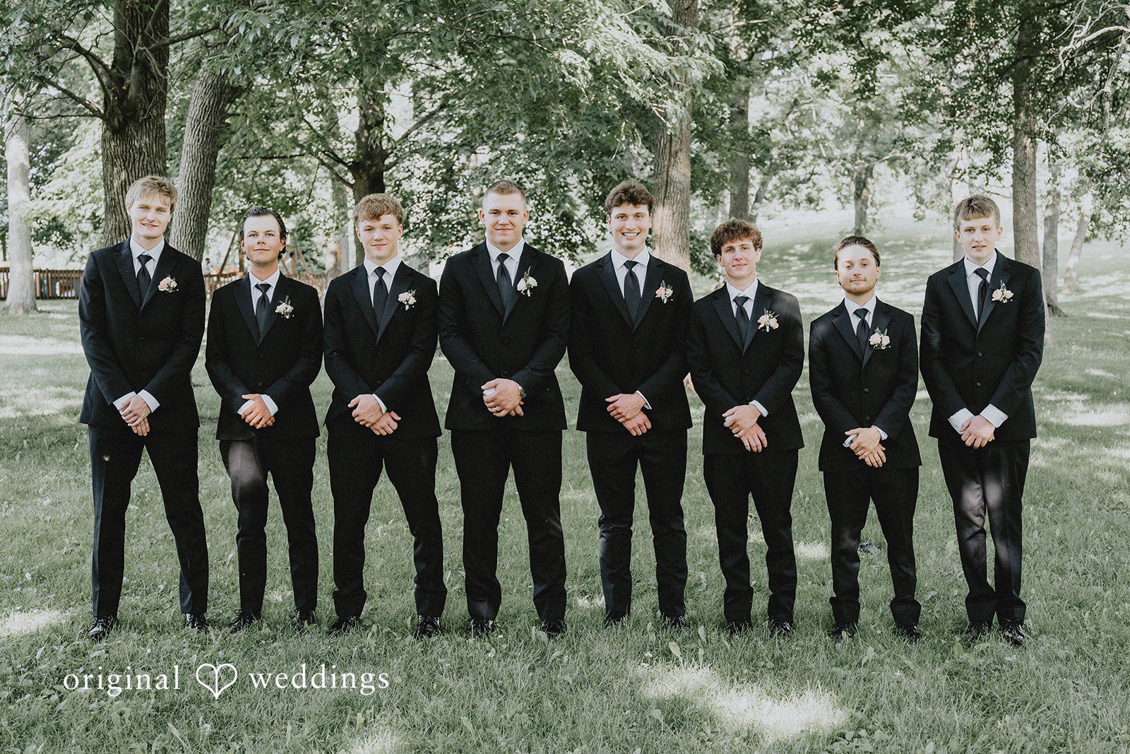Emily + Ethan Groom and groomsmen posing together in matching dark suits.