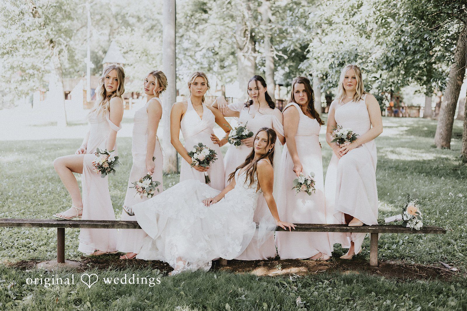 Emily + Ethan Group of bridesmaids in light-colored dresses standing in a line.