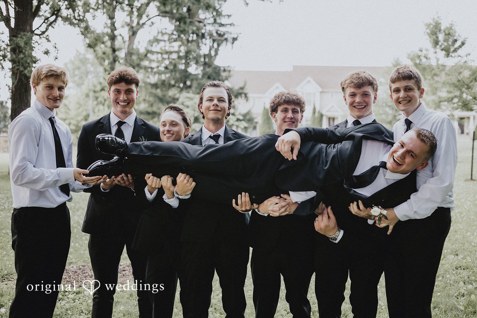 Emily + Ethan Groomsmen enthusiastically lifting the groom in celebration.