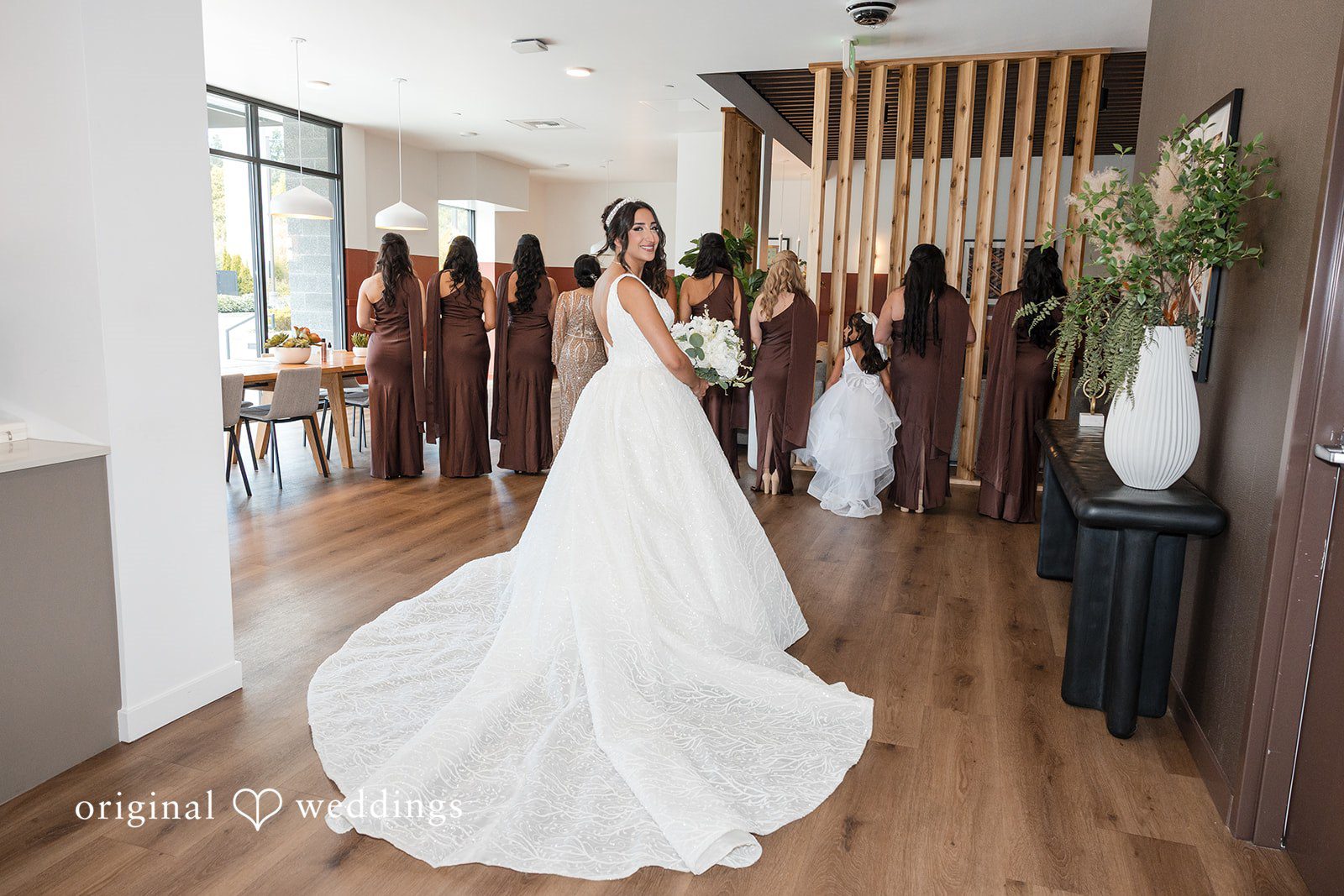 A bride walking through an entryway while bridesmaids look on.