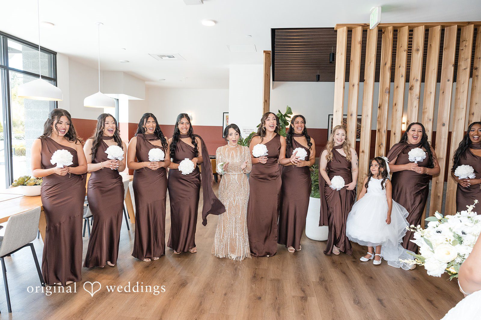 A group of bridesmaids standing in a line holding lit candles.
