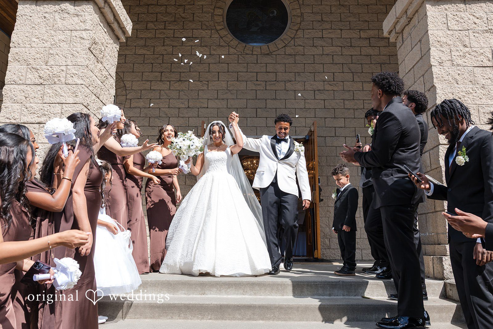 A bride and groom exiting a building while guests cheer.