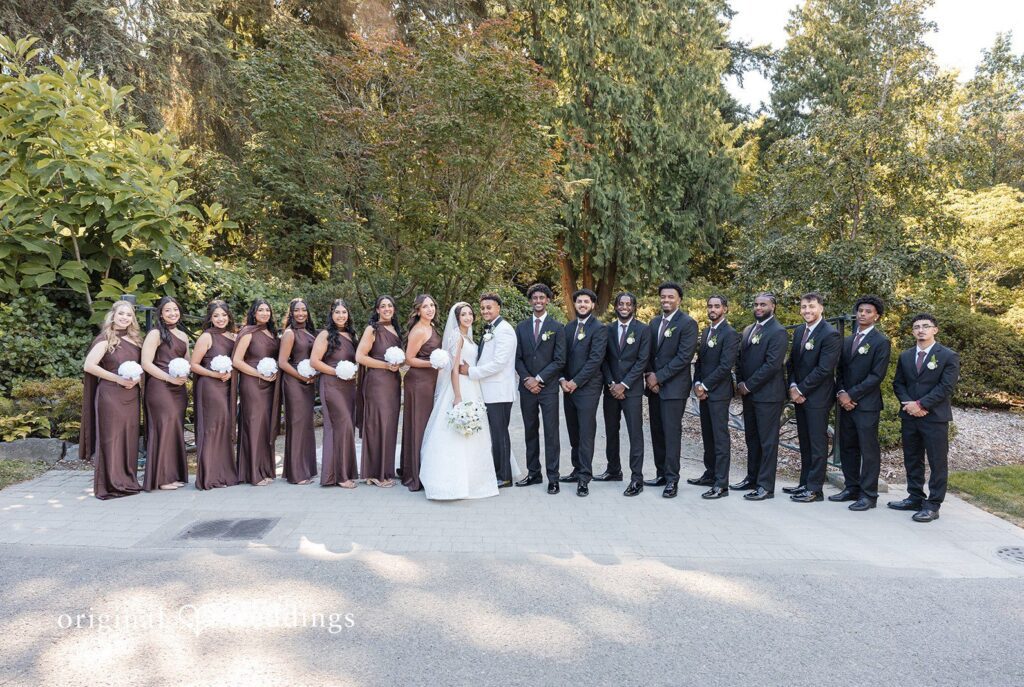 A large group portrait of the entire wedding party standing together at Aura Event Center by Seattle Wedding Photographers from Original Weddings.