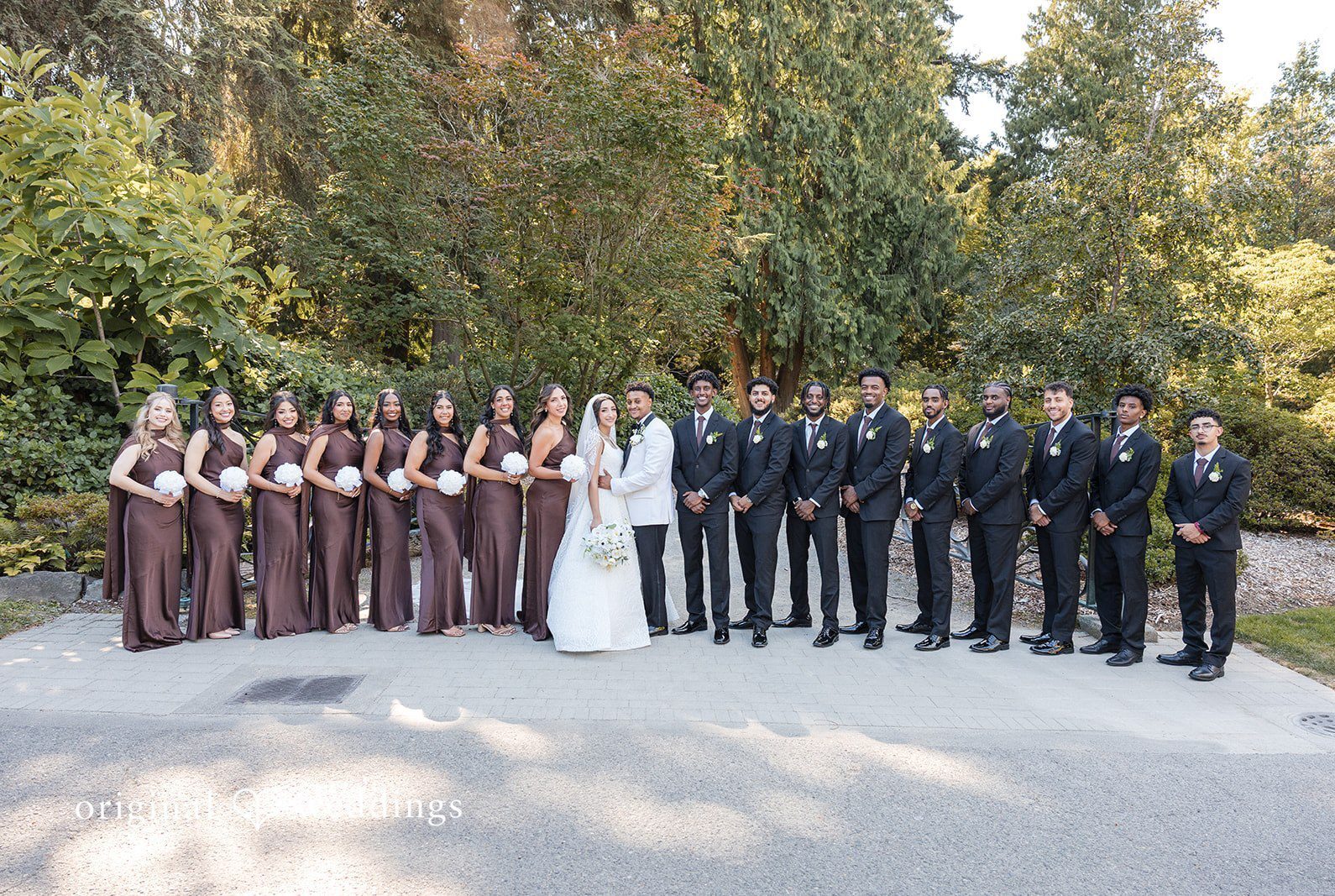 A large group portrait of the entire wedding party standing together at Aura Event Center by Seattle Wedding Photographers from Original Weddings.