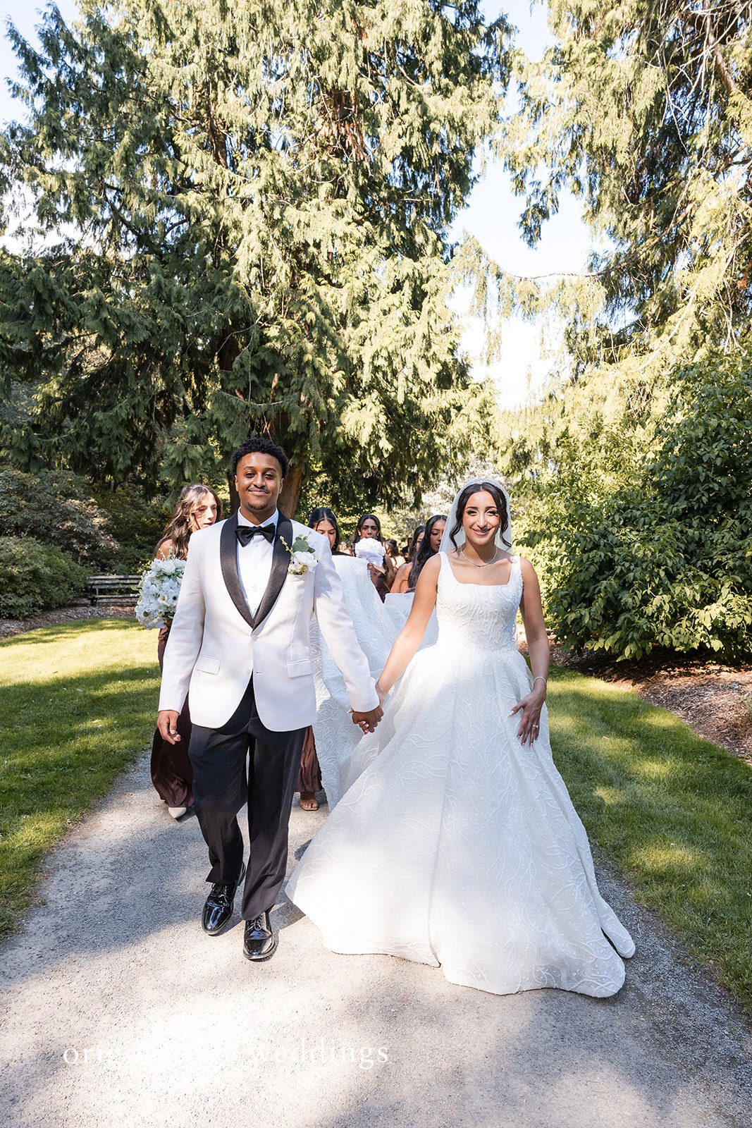 A bride and groom walking hand-in-hand down a paved path.
