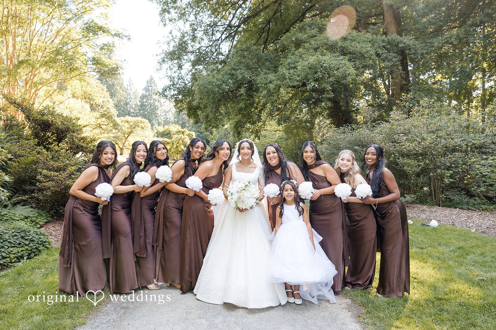 A large group of bridesmaids posing together in matching brown dresses.