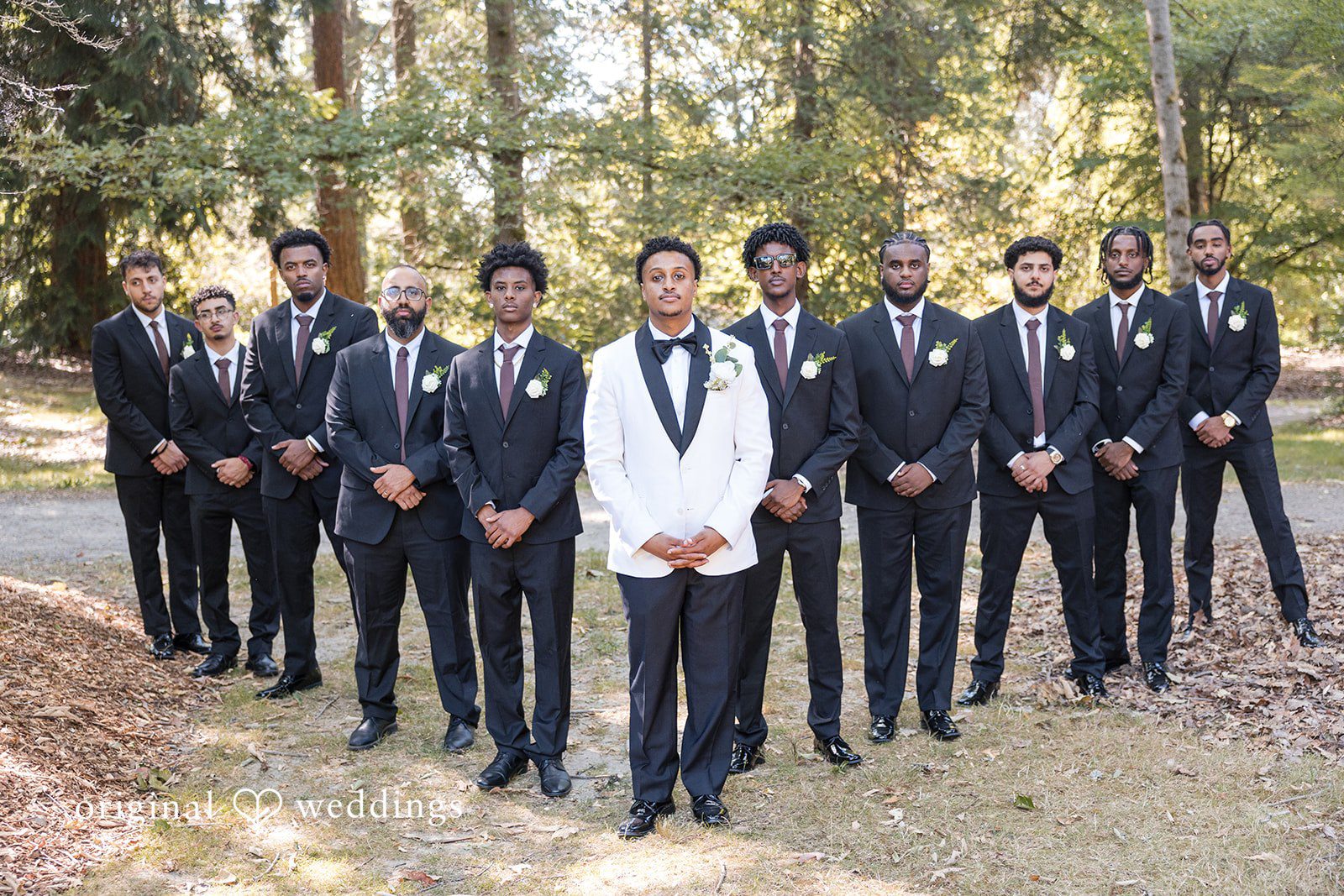 A groom and his groomsmen posing together in a forest setting.