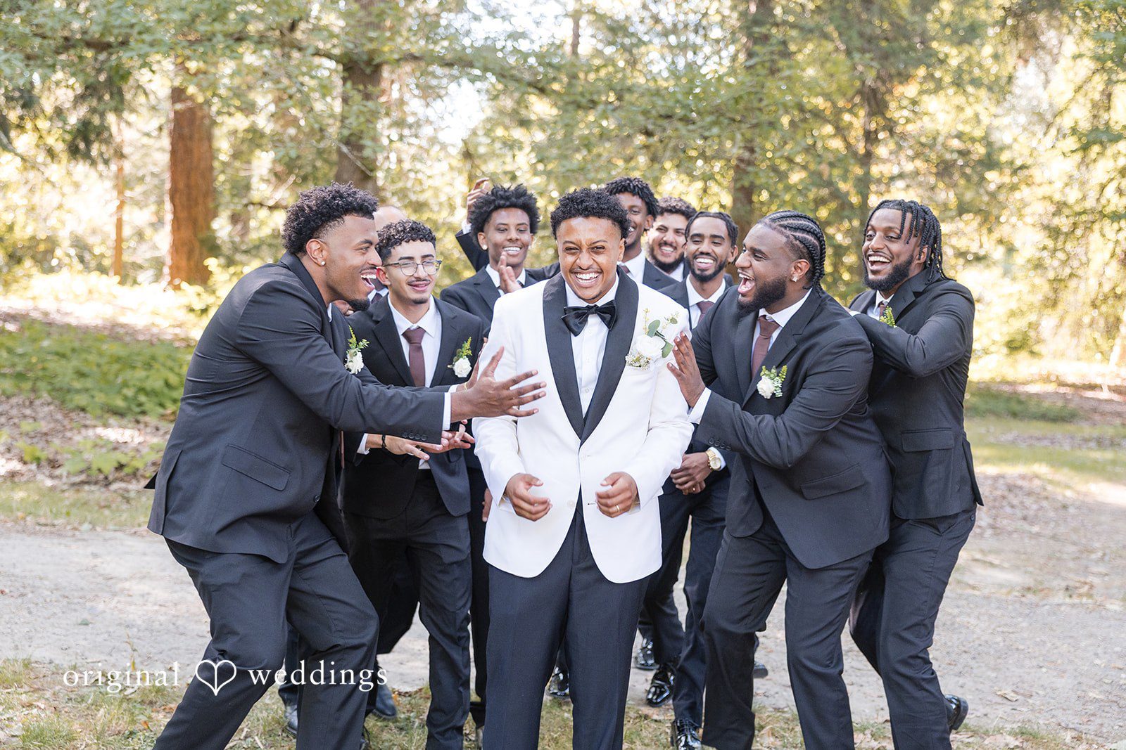 A groom laughing and celebrating with his groomsmen.