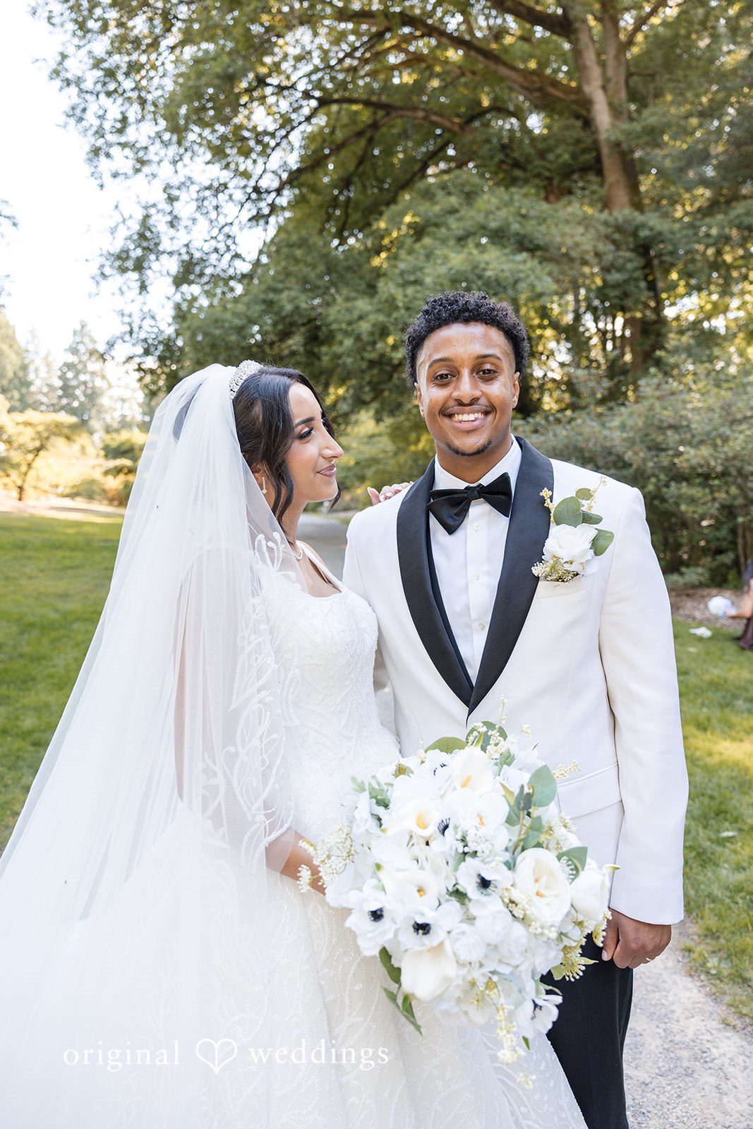 Close-up of a bride and groom smiling at each other.