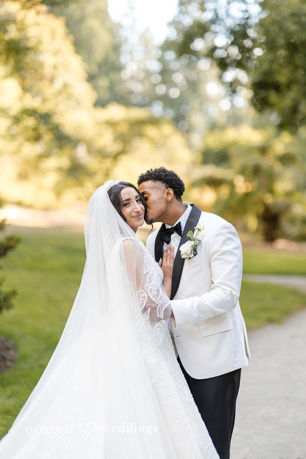 A bride and groom leaning close together on a pathway.