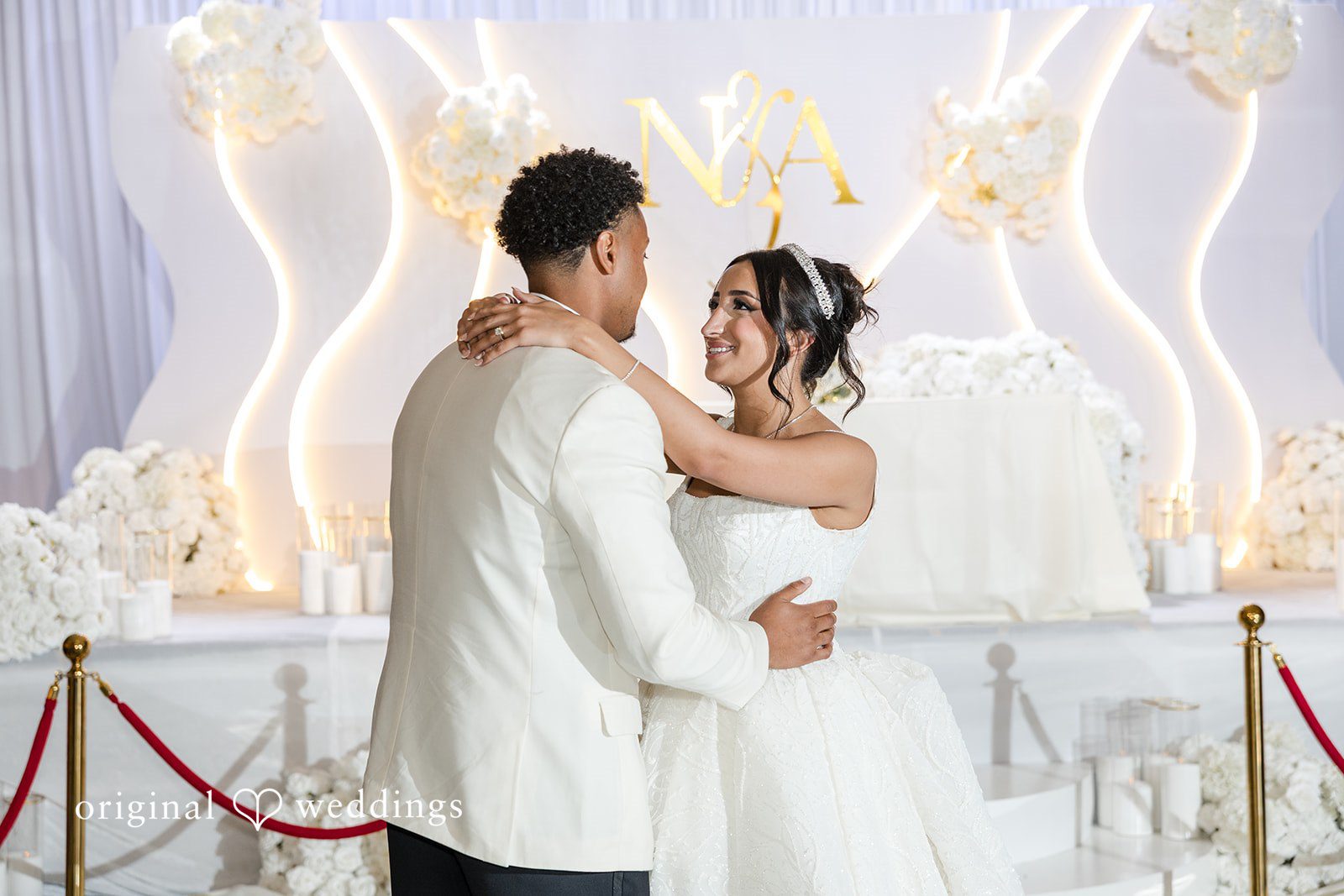 A bride and groom sharing a slow dance on a stage.