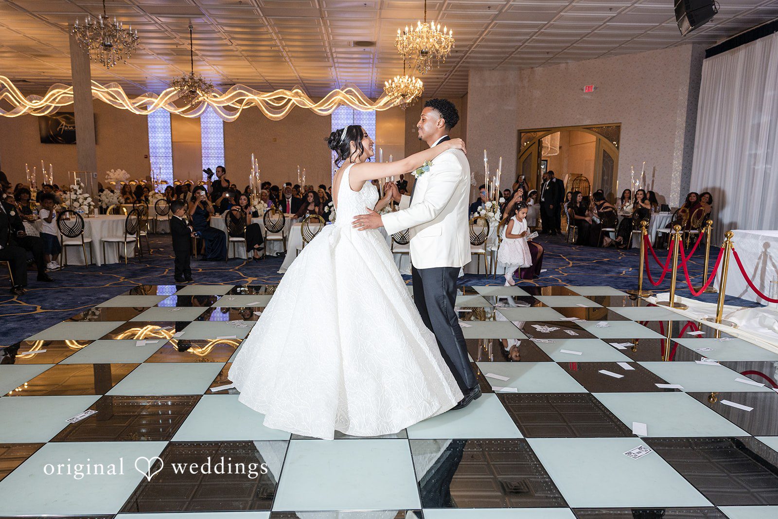 A bride and groom dancing on a checkered dance floor.